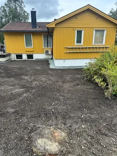 Gul enebolig med ny jordlagt hage, liten stubbe synlig i forgrunnen.